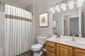 A white toilet sits in a bathroom with a white sink and a mirror.